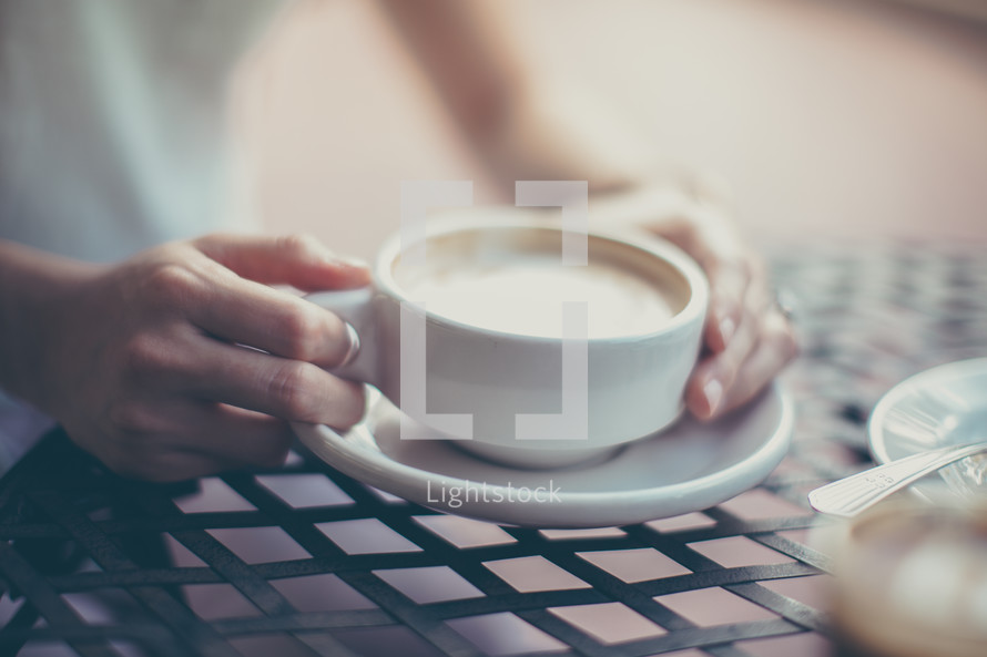 a woman holding a mug of cappuccino 