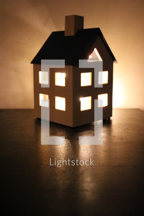 glowing candlelight in a lantern the shape of a house 