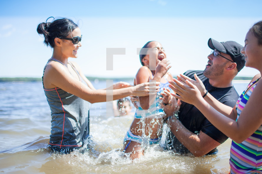 a family playing in water at the beach 