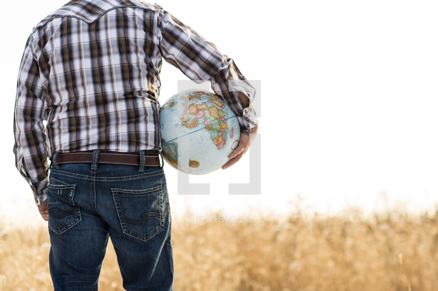 man in a field holding a globe