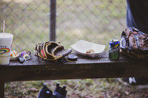 food and baseball gloves on a bench 