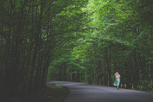 a woman walking on a tree lined road 