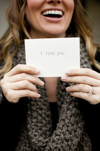 woman holding a notecard with the words I Love You 