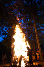 Silhouette of a man stoking a bonfire.