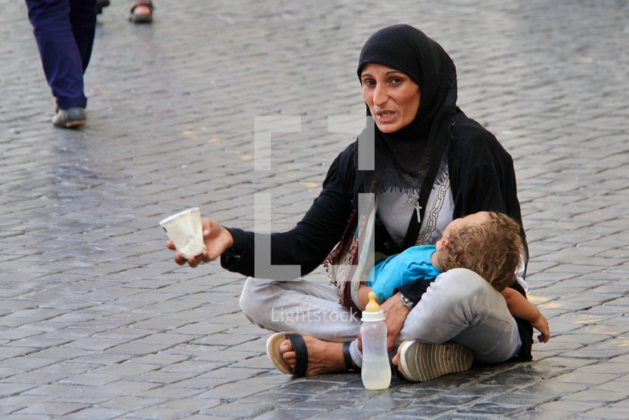 a mother holding her infant begging in Rome 