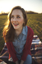 teen girl with braces sitting on a blanket outdoors
