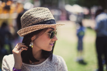 woman in a straw hat and sunglasses standing outdoors 