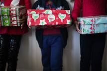 siblings holding wrapped Christmas gifts 