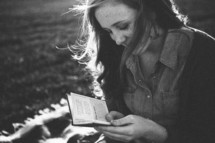teen girl sitting on a blanket reading a pocket Bible