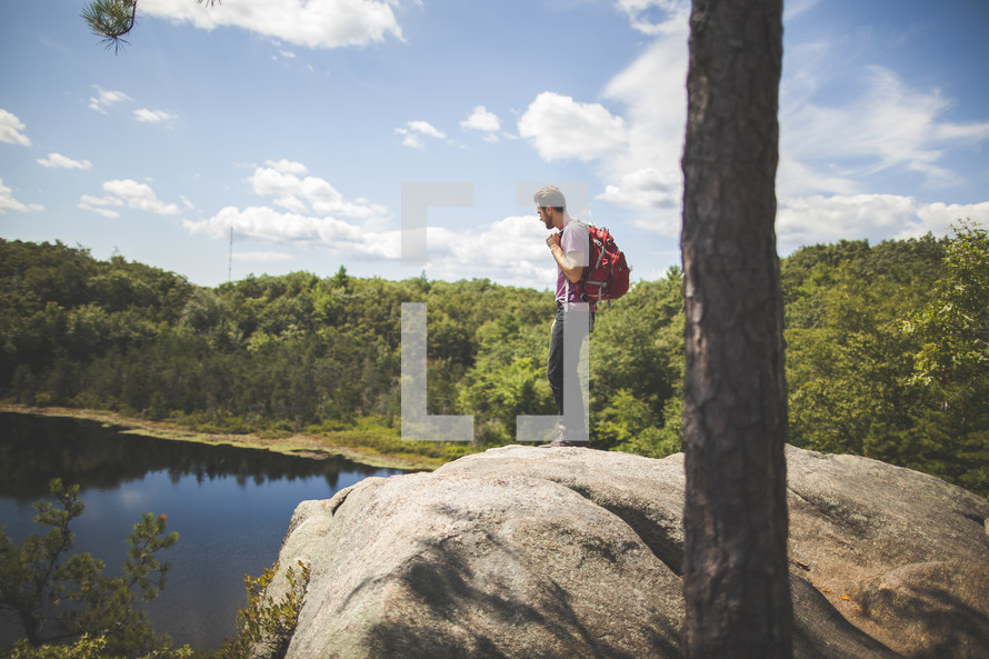 man standing on a rock looking out at a lake 