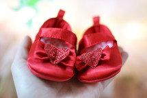 woman holding tiny red baby shoes 