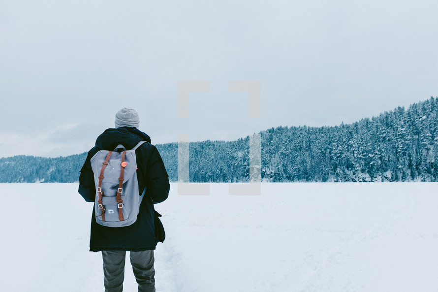 a man walking in snow with his back to the camera 