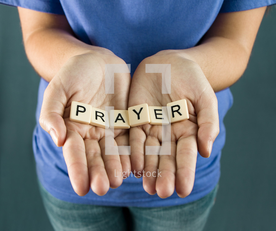 A girl holds out the word "PRAYER"