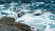 rocks along a shore and sea foam in the ocean 