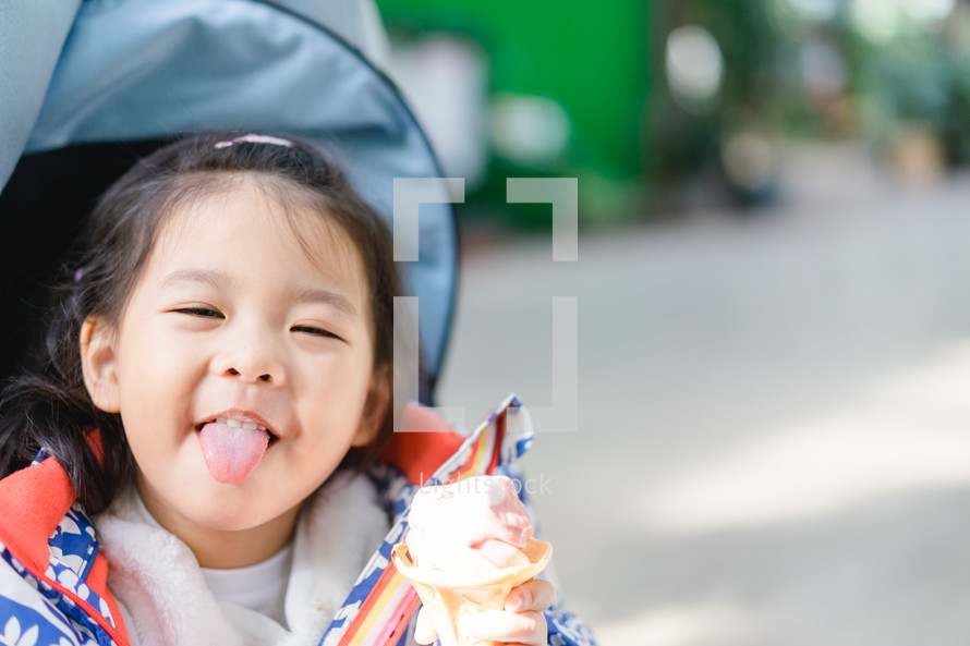 toddler girl eating ice cream in a stroller 