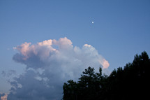 clouds and the moon in the sky over tree tops