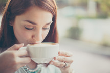 a woman sipping from a cappuccino mug 