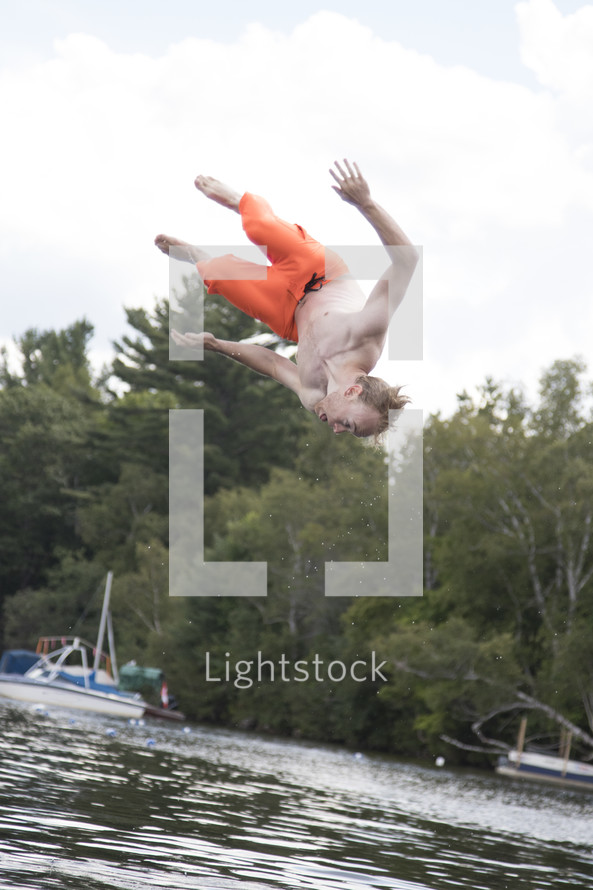 Teenage boy doing a flip over open water and upside down