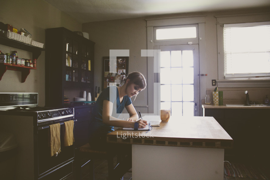 a woman writing a letter in her kitchen