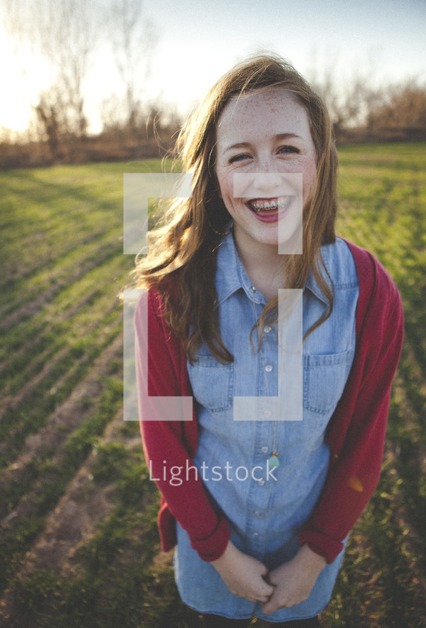 smiling teen girl with braces standing in a field