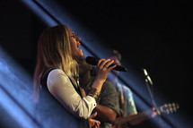 a woman singing into a microphone on stage 