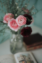 vase of pink flowers and opened book 