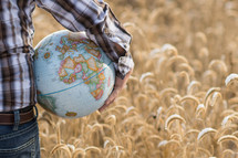 man holding a globe standing in a field 