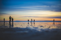 people standing on a beach at sunset 