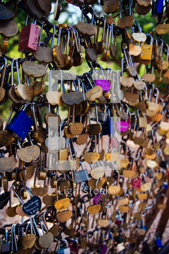 Many heart shaped locks attached to a chain fence.