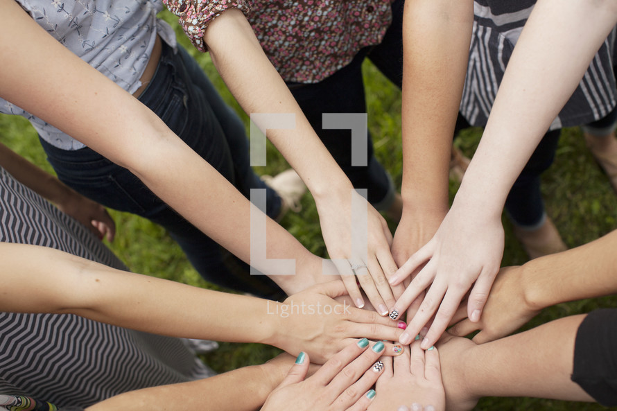 A group of girls bond as they put their hands together.