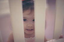 face of a young girl looking into a crib at her baby sister 