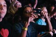 teens in an audience taking pictures with cellphones