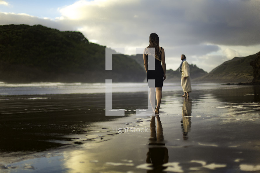 A woman standing on a beach and Jesus looking back at her 