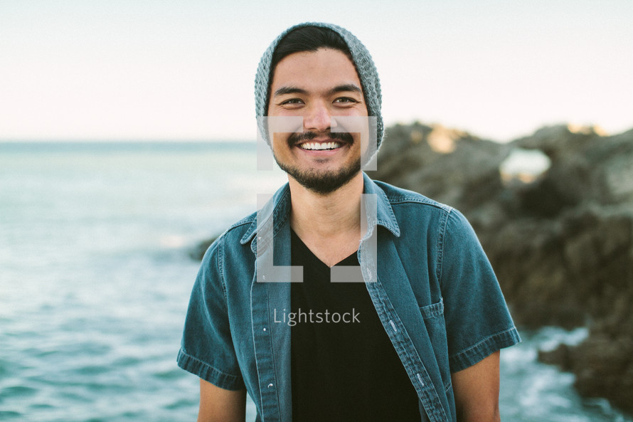 a smiling man standing on a shore 