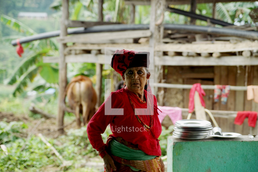 a woman washing dishes outside in a village 