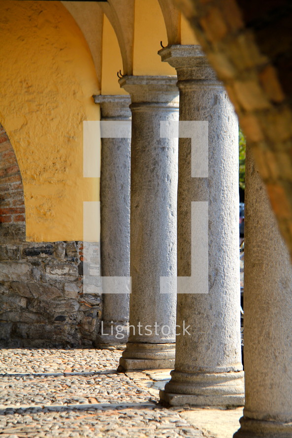 Stone columns in a medieval building with cobbled stone paving 