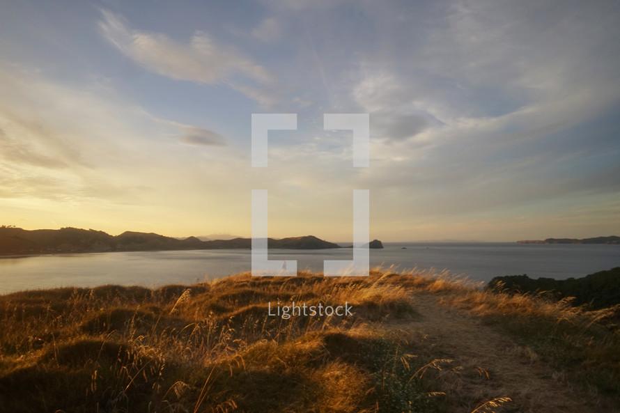 hill with grass along a shore at sunset 