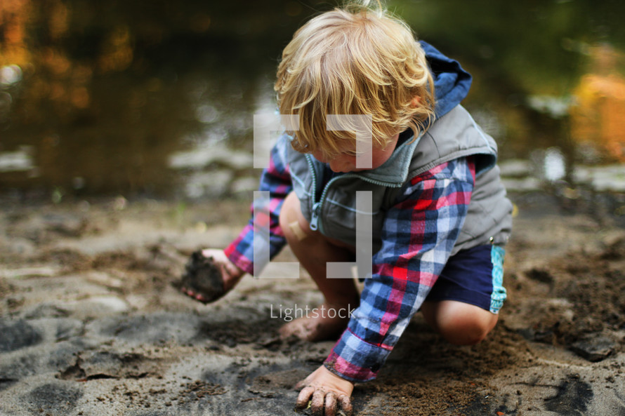 toddler boy playing with dirt and rocks 