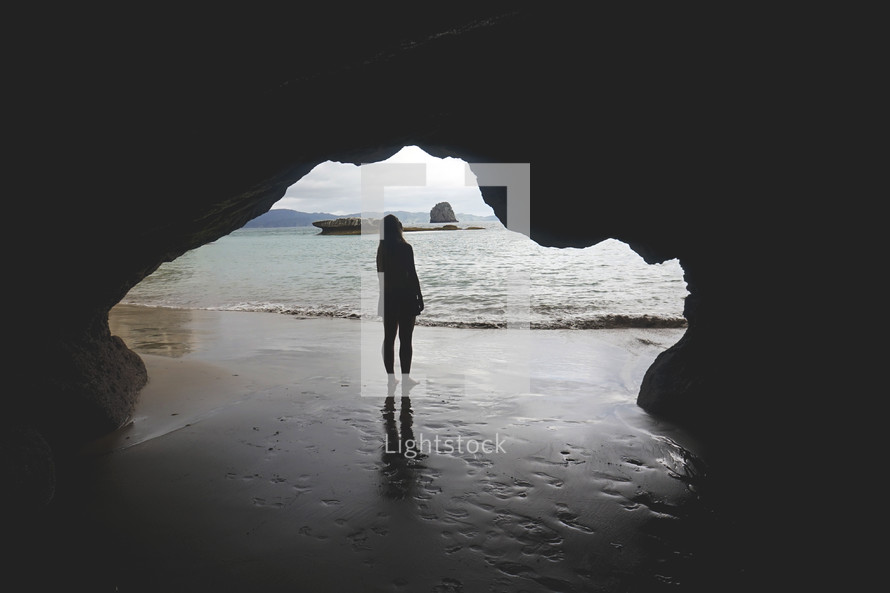 woman standing in a cave on a beach 