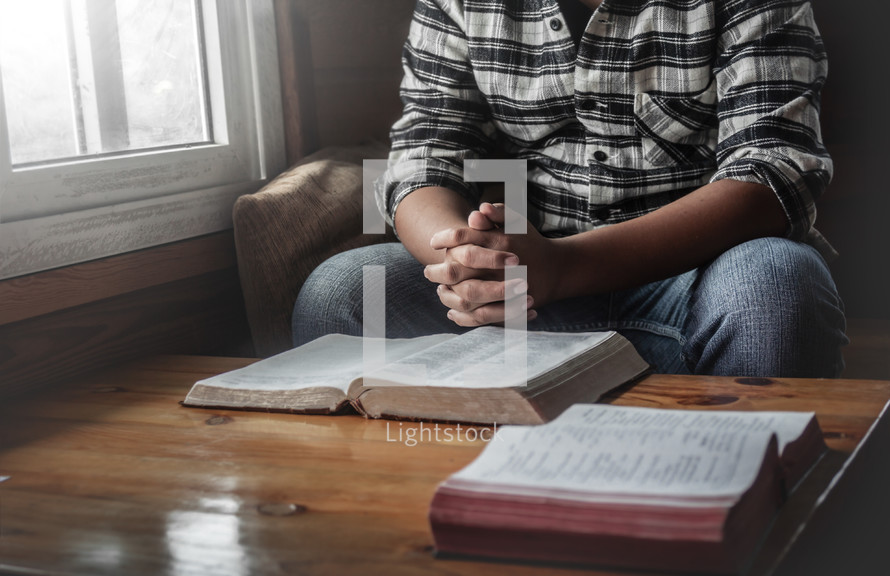 a man sitting in a window praying over a Bible 