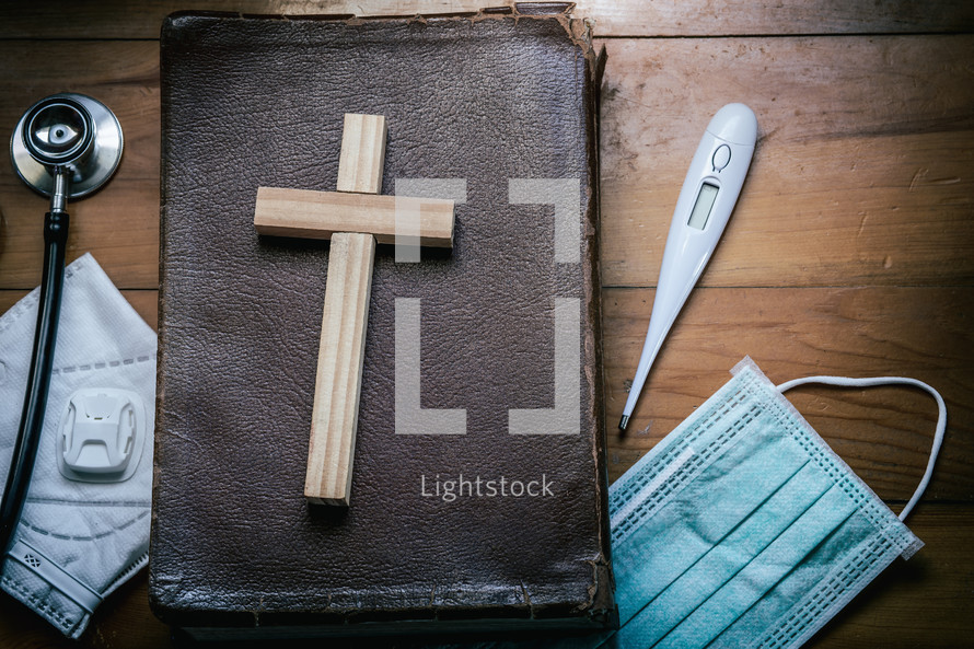Bible, face mask, wooden cross, and stethoscope 