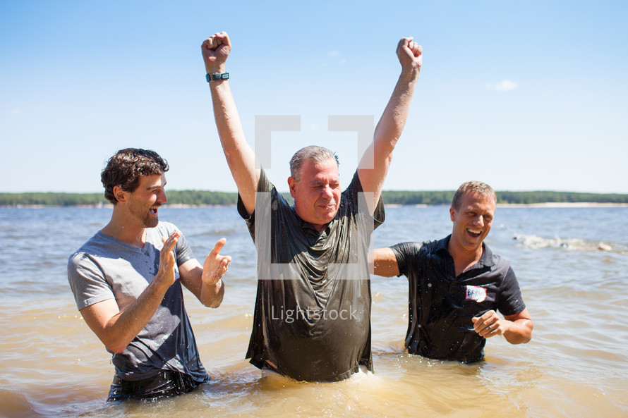 a man celebrating after his baptism in water outdoors 