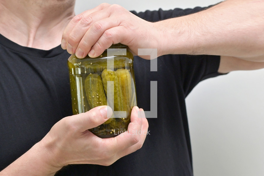 Man Hard Try To Remove Cover From Cucumbers Jar