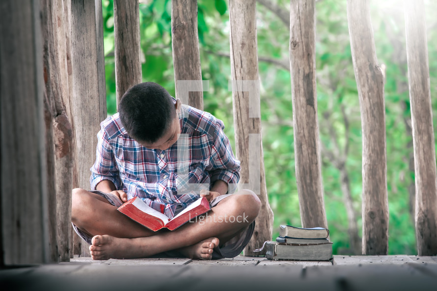 a boy reading a Bible outdoors 