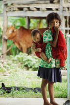 a girl standing barefoot with a baby on her back 