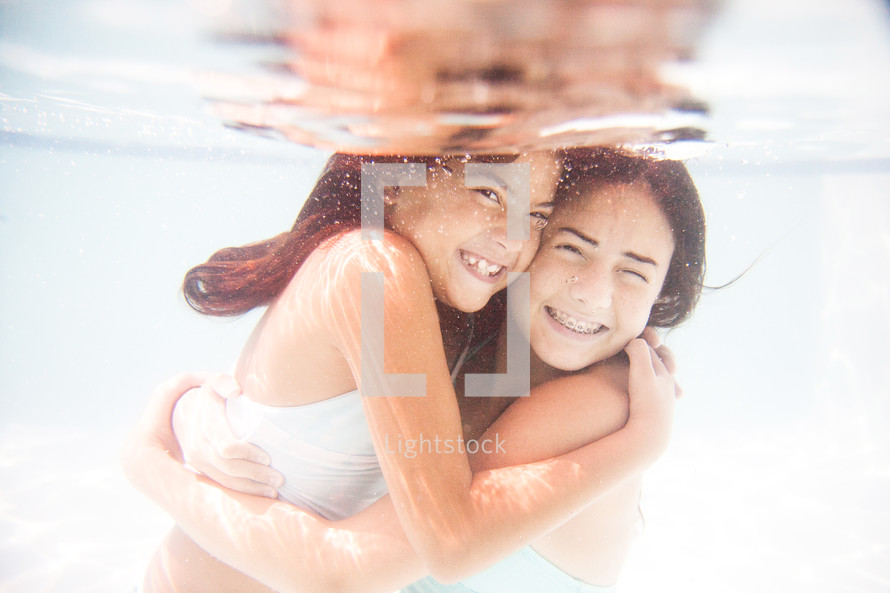 girls hugging under water 