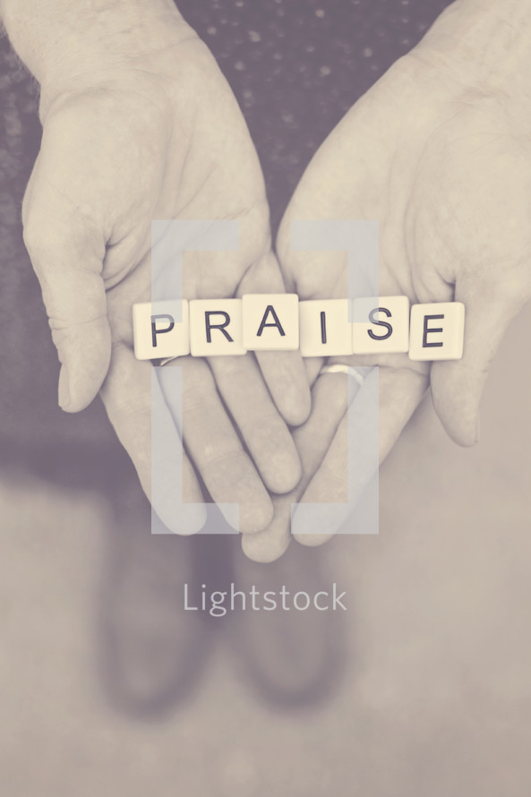 word praise in scrabble pieces in a woman's hands 