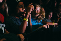 teens in an audience taking pictures with cellphones 