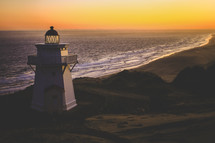 a lighthouse on a shore at sunset 
