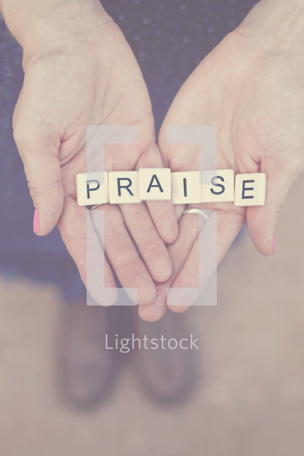 word praise in scrabble pieces in a woman's hands 